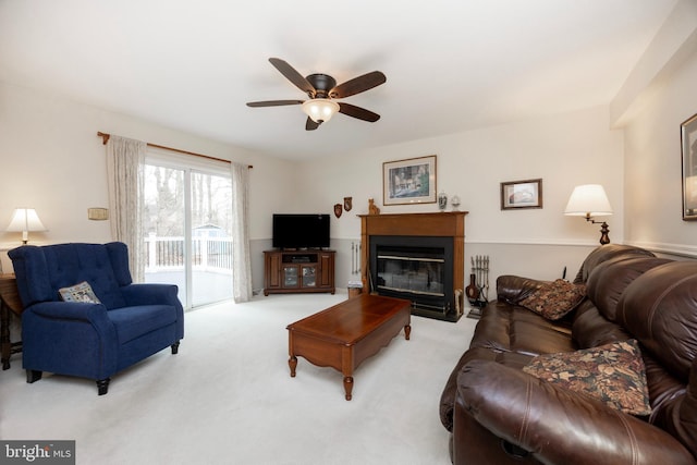 carpeted living room with a glass covered fireplace and ceiling fan