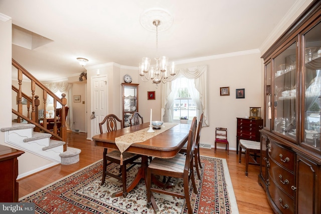 dining space featuring a notable chandelier, light wood-style flooring, ornamental molding, baseboards, and stairs