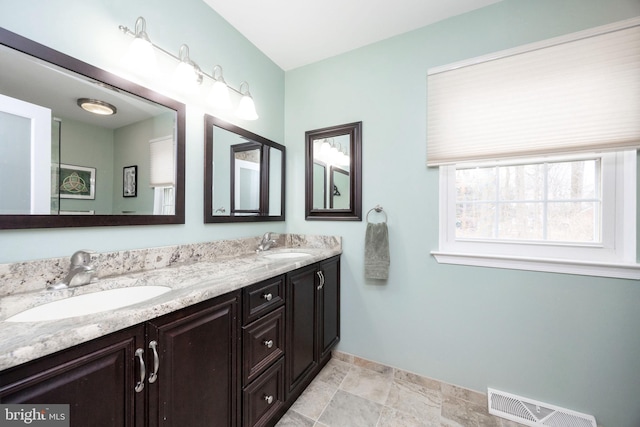 full bathroom featuring double vanity, visible vents, baseboards, and a sink