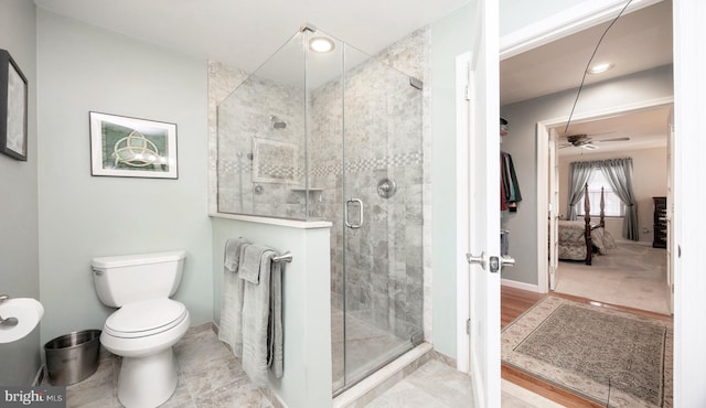 ensuite bathroom featuring a stall shower, toilet, ensuite bathroom, and baseboards