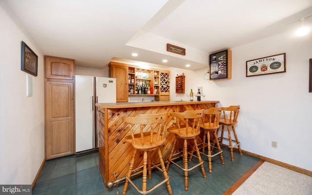 bar with bar, recessed lighting, baseboards, and freestanding refrigerator