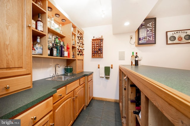 bar with indoor wet bar, dark tile patterned flooring, baseboards, and a sink