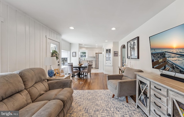 living area featuring recessed lighting, arched walkways, and wood finished floors