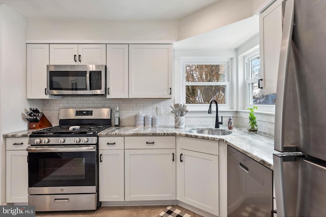 kitchen with white cabinetry, appliances with stainless steel finishes, decorative backsplash, and a sink