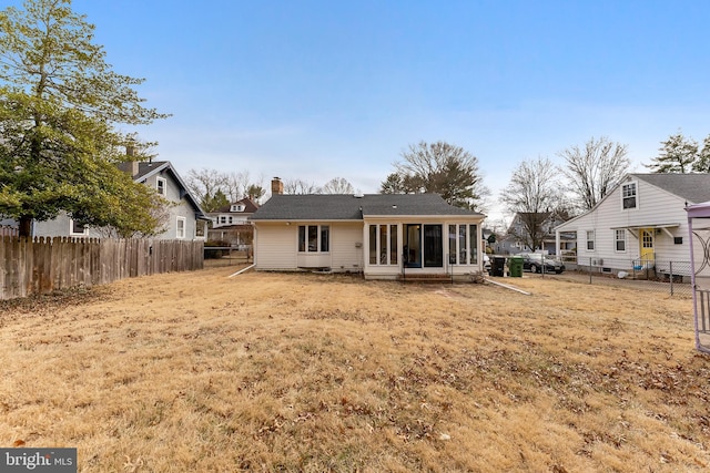 rear view of house featuring a sunroom, a fenced backyard, and a chimney