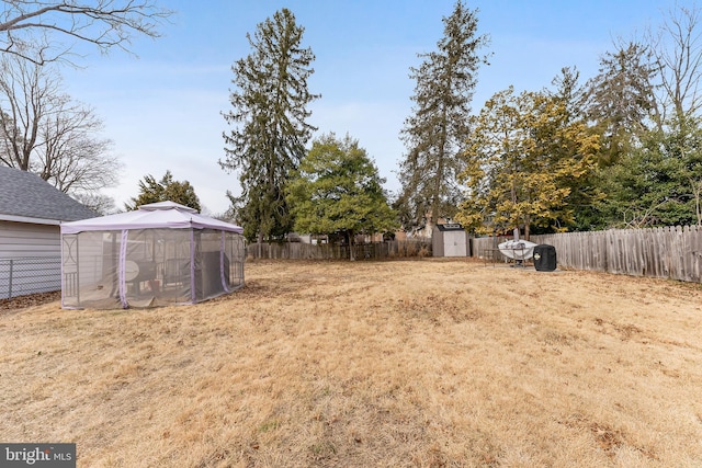 view of yard with a storage shed, a fenced backyard, and an outbuilding