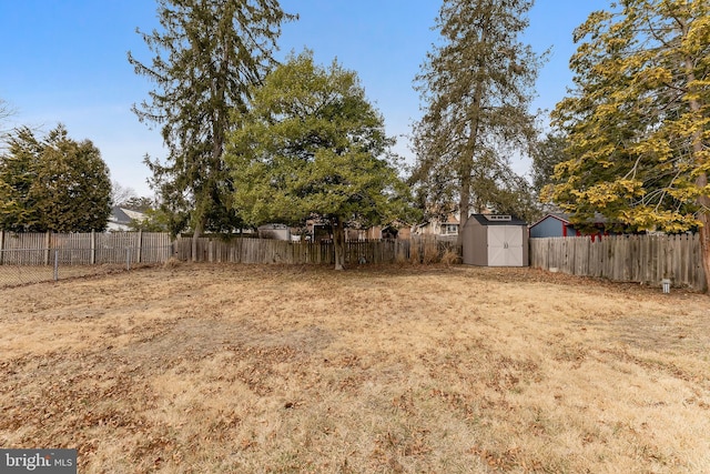 view of yard featuring an outbuilding, a fenced backyard, and a storage shed