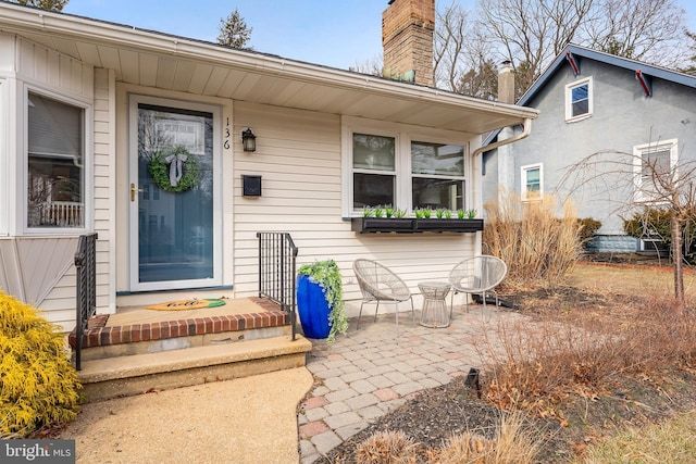 doorway to property with a patio area and a chimney