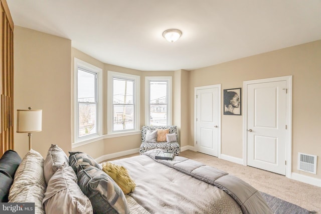 bedroom featuring baseboards, visible vents, and light colored carpet