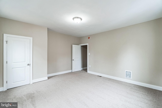 empty room with carpet floors, visible vents, and baseboards