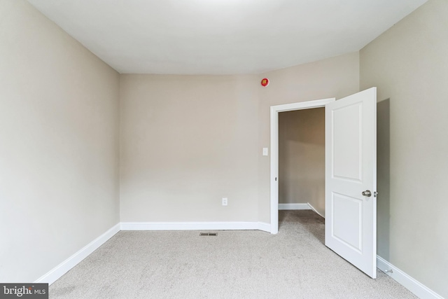 spare room with light carpet, visible vents, and baseboards