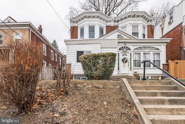 italianate house featuring brick siding and fence