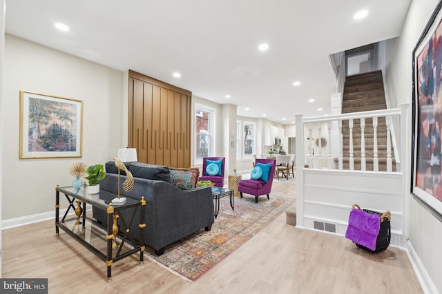 living area with recessed lighting, visible vents, light wood-style flooring, baseboards, and stairs