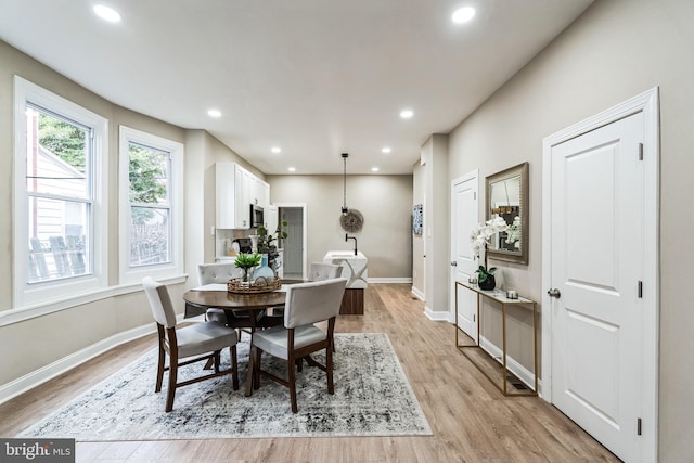 dining space with baseboards, light wood finished floors, and recessed lighting