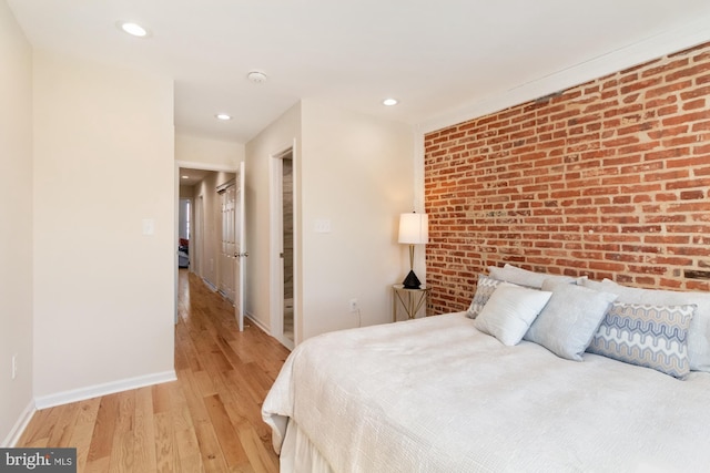 bedroom with recessed lighting, baseboards, light wood-style flooring, and brick wall