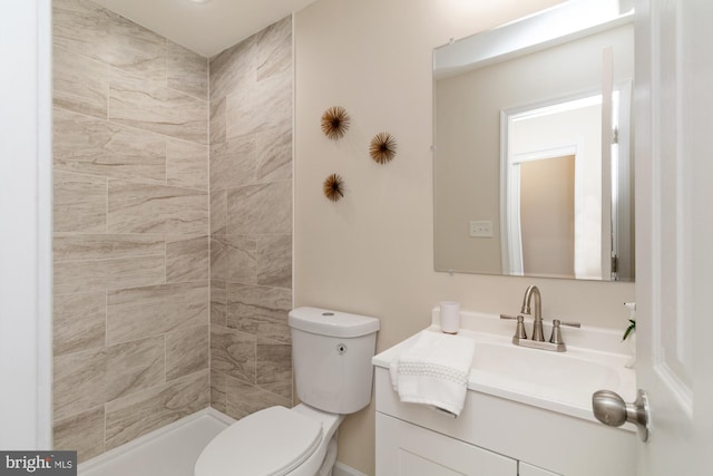 full bathroom with tiled shower, toilet, and vanity