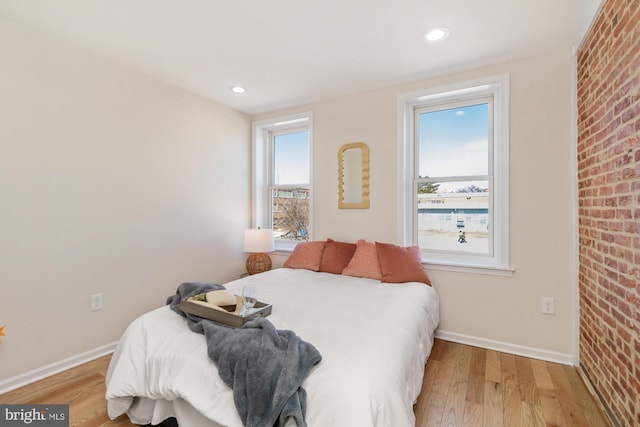 bedroom featuring recessed lighting, brick wall, light wood-type flooring, and baseboards