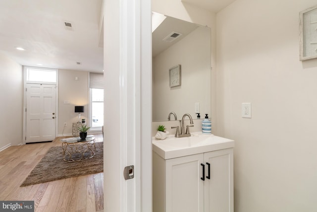 bathroom featuring visible vents, vanity, baseboards, and wood finished floors