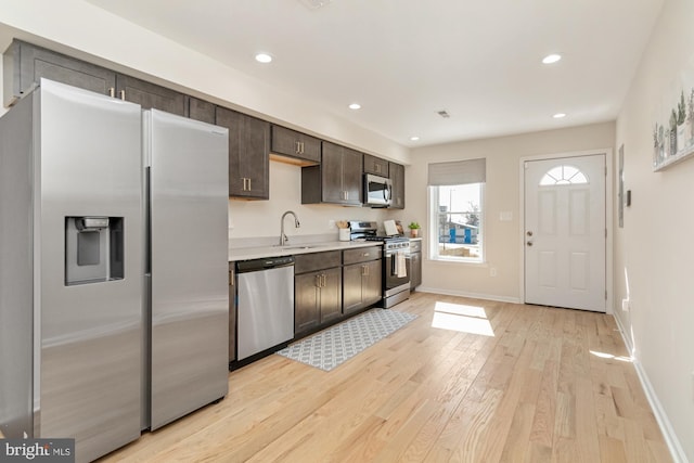 kitchen featuring light wood-style flooring, a sink, stainless steel appliances, light countertops, and dark brown cabinetry