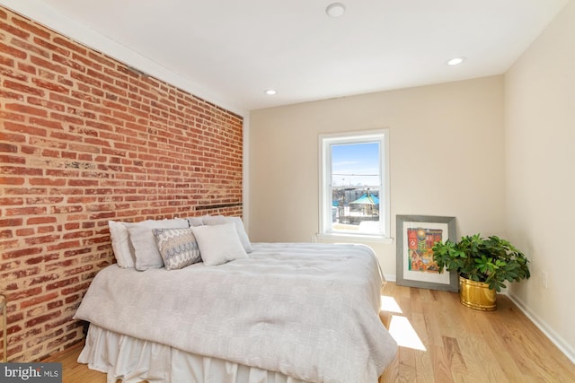 bedroom featuring recessed lighting, light wood-style floors, baseboards, and brick wall