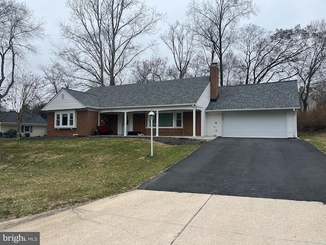 ranch-style house featuring brick siding, an attached garage, a front lawn, a chimney, and driveway