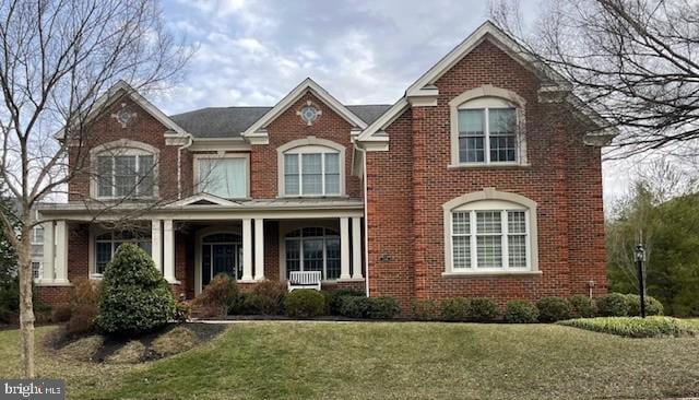 view of front of home with brick siding, a porch, and a front yard