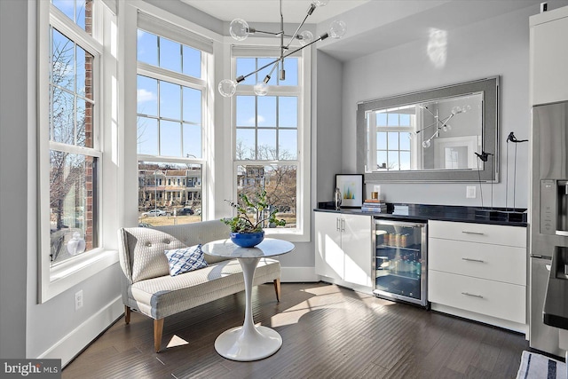 bar featuring dark wood-style flooring, baseboards, beverage cooler, oven, and stainless steel fridge with ice dispenser