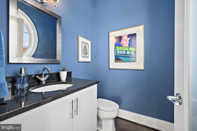 bathroom with toilet, baseboards, and vanity