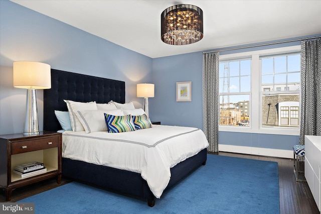 bedroom with a chandelier, multiple windows, baseboards, and wood finished floors