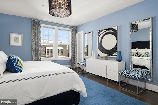 bedroom with wood finished floors and a notable chandelier