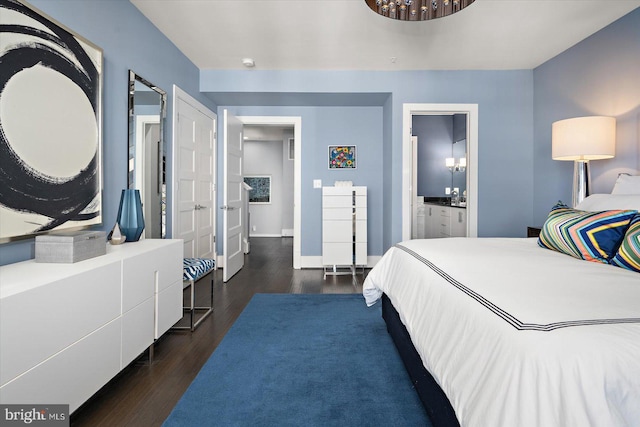 bedroom featuring ensuite bath, baseboards, and dark wood-style flooring