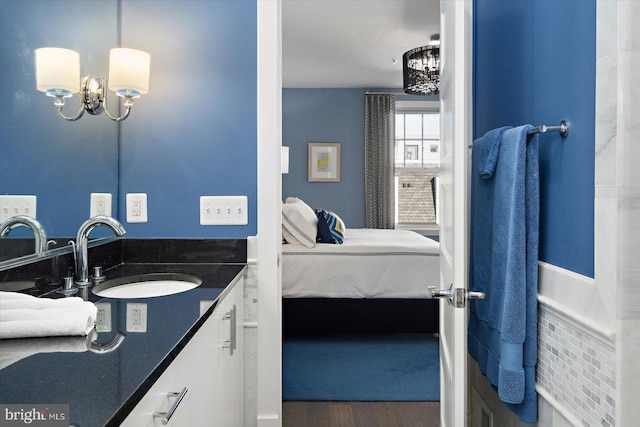 bathroom with a notable chandelier, connected bathroom, vanity, and wood finished floors