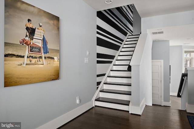 stairs with baseboards, visible vents, and wood finished floors