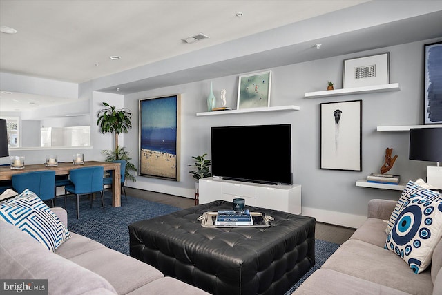 living room with baseboards, visible vents, and wood finished floors