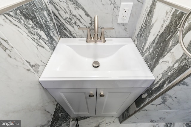 bathroom featuring stone wall, marble finish floor, and vanity