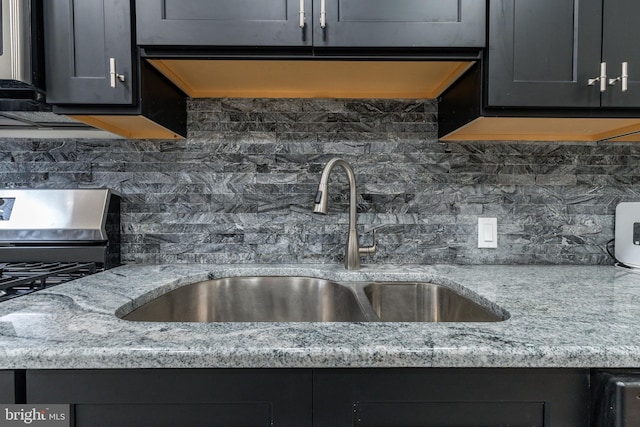 kitchen featuring a sink, decorative backsplash, and light stone countertops