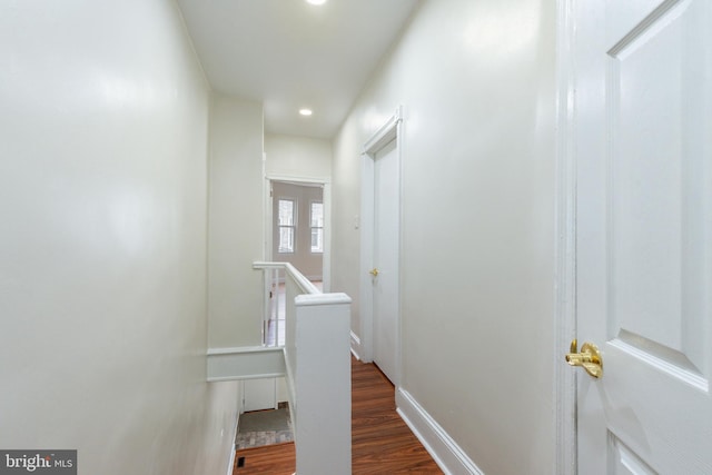 corridor featuring dark wood-style floors, an upstairs landing, and baseboards