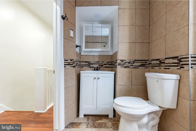 bathroom with tile walls, toilet, and a sink