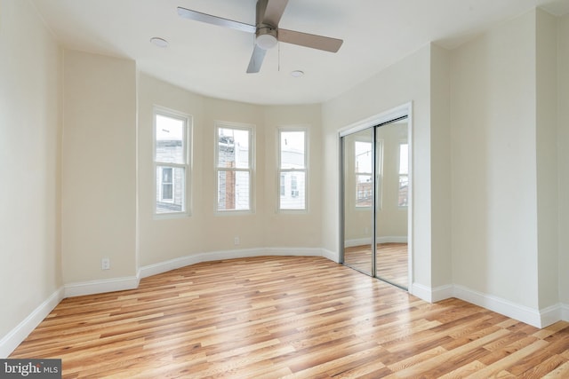 unfurnished bedroom with a closet, light wood-style flooring, baseboards, and ceiling fan