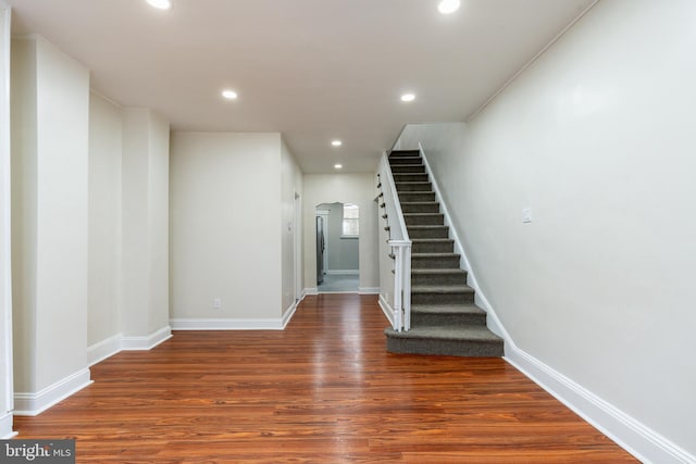 interior space featuring recessed lighting, baseboards, arched walkways, and wood finished floors