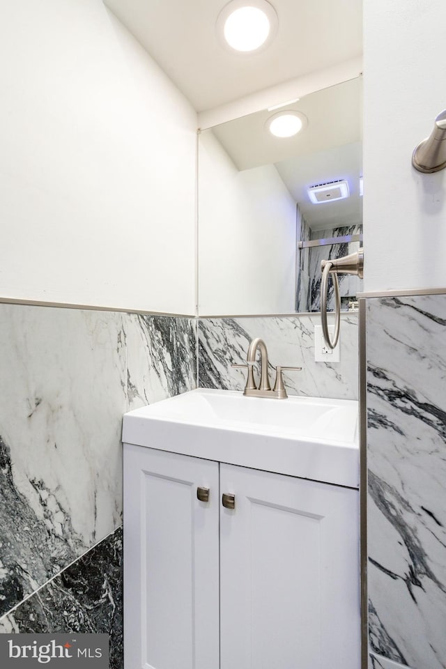 interior space with visible vents, tile walls, a wainscoted wall, and vanity