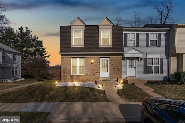 townhome / multi-family property featuring brick siding, a shingled roof, and a front yard