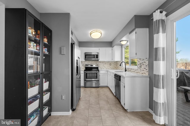 kitchen featuring decorative backsplash, stainless steel appliances, light countertops, and a sink