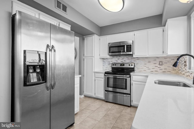 kitchen featuring tasteful backsplash, visible vents, stainless steel appliances, and a sink