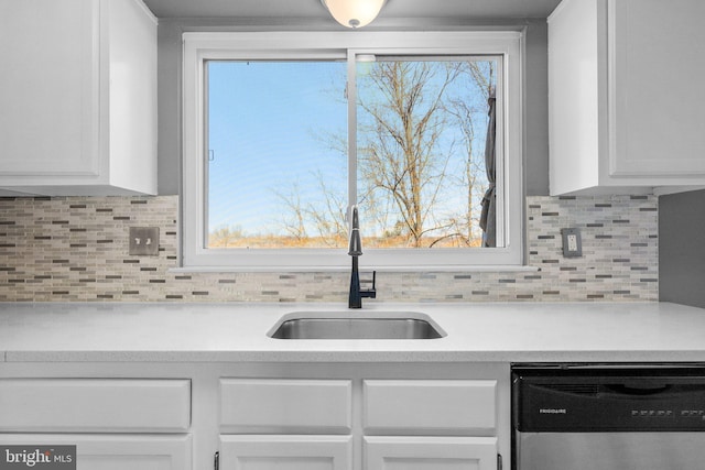 kitchen with dishwasher, light countertops, white cabinets, and a sink