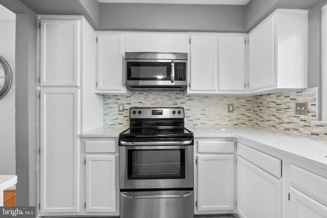 kitchen with decorative backsplash, white cabinetry, and stainless steel appliances