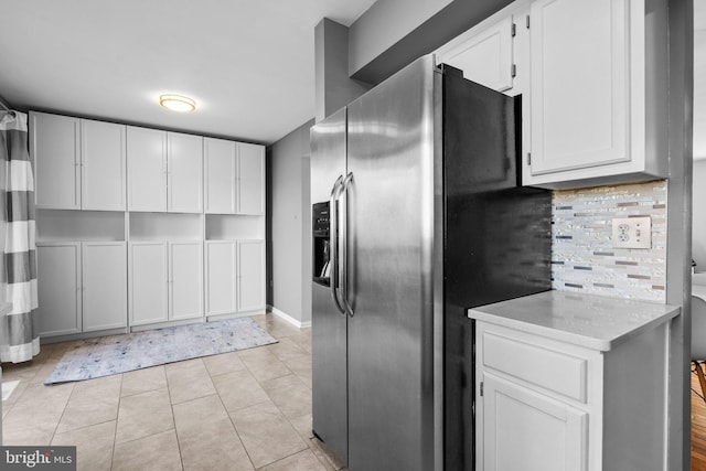 kitchen featuring backsplash, white cabinetry, stainless steel fridge with ice dispenser, light countertops, and light tile patterned floors