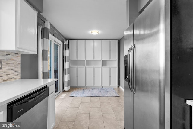 kitchen with backsplash, stainless steel appliances, white cabinets, light countertops, and light tile patterned floors