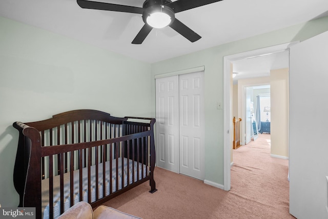 bedroom featuring a closet, a nursery area, carpet flooring, baseboards, and ceiling fan