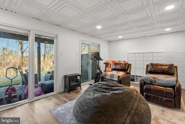 interior space featuring light wood finished floors, an ornate ceiling, brick wall, and a wood stove